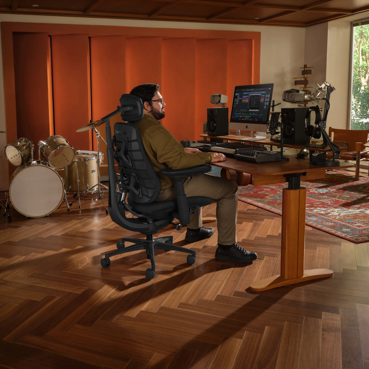 Bürostuhl LiberNovo Maxis Airflow in Graphit an einem höhenverstellbaren Schreibtisch in einem Musikstudio von Libernovo