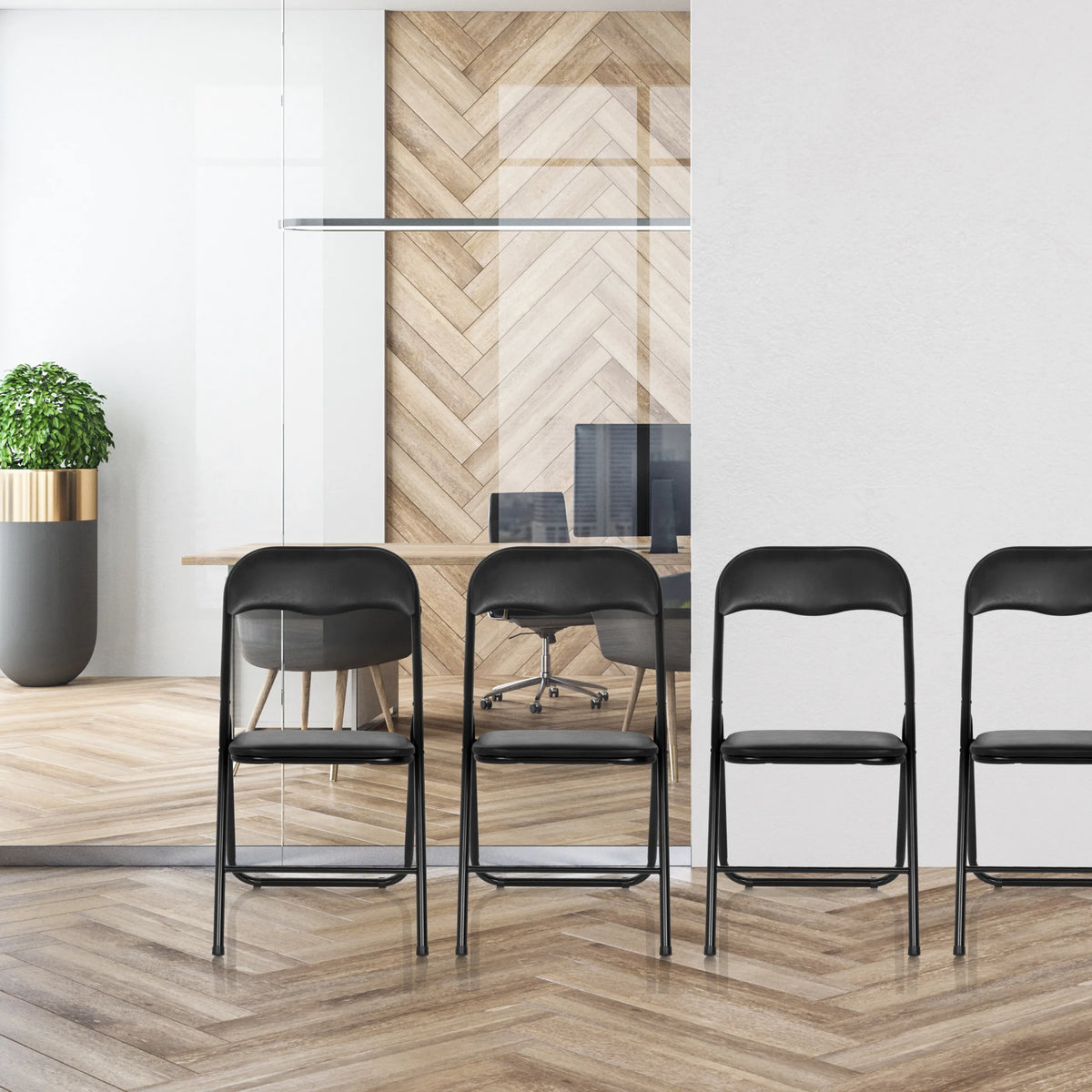 Vier schwarze Klappstühle TUDELA BASIC aus PVC in einer Reihe vor einer Glaswand von hjh OFFICE